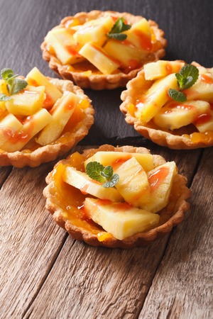 Tartlets with pineapple, jam and mint close-up on the table. vertical
の写真素材