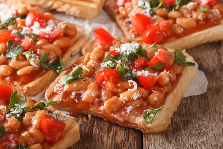 toasts with beans in a tomato sauce, cheese and herbs closeup on the table. Horizontal
の写真素材