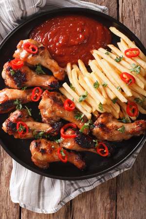 Grilled chicken wings with french fries and ketchup on the table close-up. vertical view from above
の写真素材
