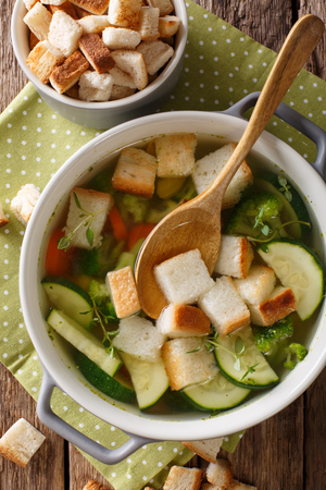 Light dietary soup with croutons close-up in a saucepan on a table. Vertical view from aboveの写真素材