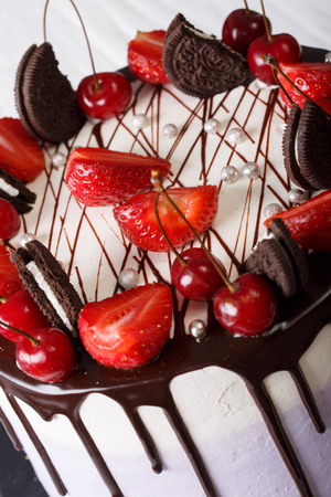 Mousse cake with fresh strawberries and cherries, decorated with biscuits and chocolate close-up. verticalの写真素材