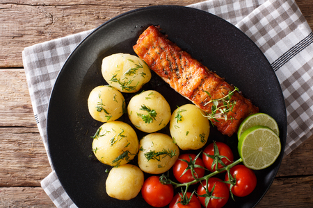 grilled salmon and boiled new potatoes with butter and herbs closeup on a plate. horizontal view from aboveの写真素材