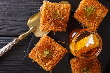 Kataif cake with pistachios and fresh honey close-up on a table. horizontal view from aboveの写真素材