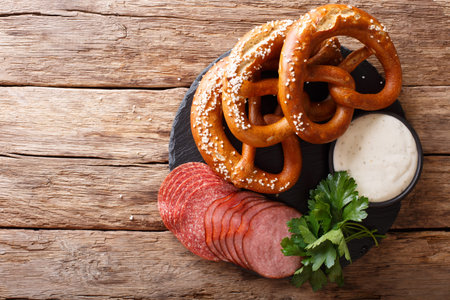 German food: sliced sausages and pretzels with cream sauce close-up on the table. horizontal view...