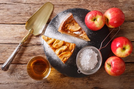 Delicious piece of apple pie with powdered sugar and juice close-up on the table. horizontal view from aboveの写真素材