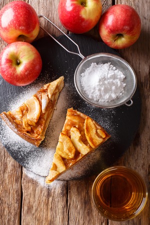 Cut freshly baked apple pie with powdered sugar close-up on the table. vertical view from aboveの写真素材