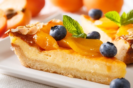A beautiful dessert: a cheesecake with apricots, blueberries and almonds close-up on a plate. horizontalの写真素材