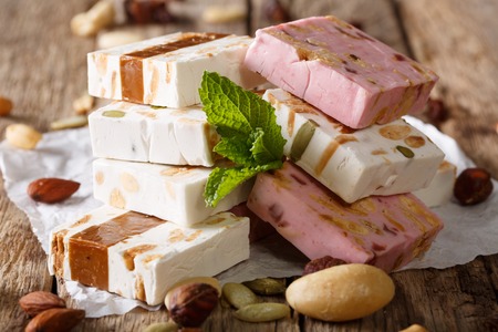 White, pink and brown nougat with nuts and mint closeup on the table. Horizontal, rusticの写真素材