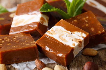 Candy toffee with almonds, decorated with fresh crumpled macro on parchment on the table. Horizontalの写真素材
