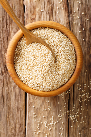 Raw quinoa close up in a wooden bowl on the table. top view from above vertical backgroundの写真素材