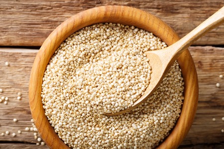Traditional raw quinoa close up in a wooden bowl on the table. top view from above horizontal backgroundの写真素材