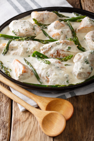 sliced chicken with baby asparagus in cream sauce close-up on a plate on the table. verticalの写真素材