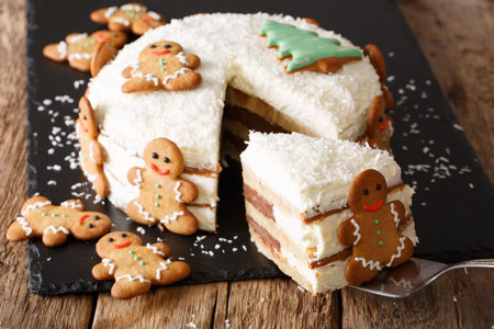 piece of Christmas cake with cheese cream is decorated with gingerbread close-up on the table....