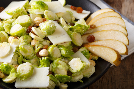 Healthy food: salad from Brussels sprouts, hazelnuts, cheese, raisins and pears closeup on a plate. horizontal
の写真素材