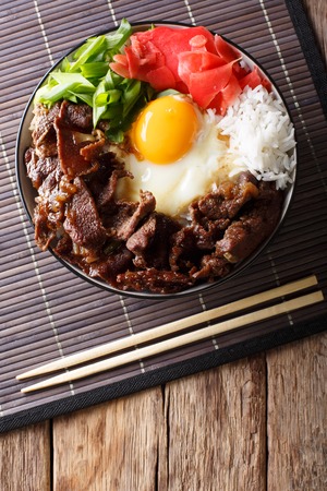 Gyudon beef with rice, egg and onion closeup in a bowl on the table. Vertical top view from above, rustic
の写真素材