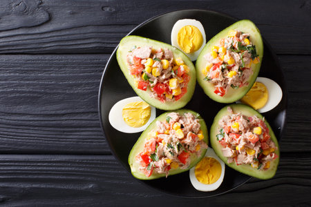 Delicious snack of avocado stuffed with tuna salad closeup on a plate. horizontal top view from...