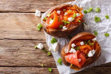 Healthy food: sweet potato stuffed with salmon, feta cheese and green onions close-up on parchment on the table. horizontal top view from above
の写真素材