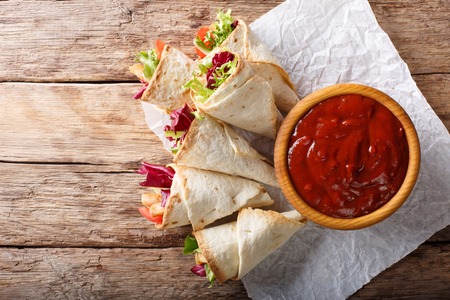 Delicious burrito with turkey, lettuce and vegetables close-up on the table. horizontal top view from above
の写真素材
