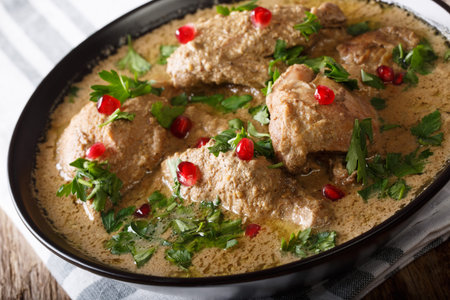 Georgian spicy satsivi with chicken and pomegranate close-up in a bowl on the table. horizontal