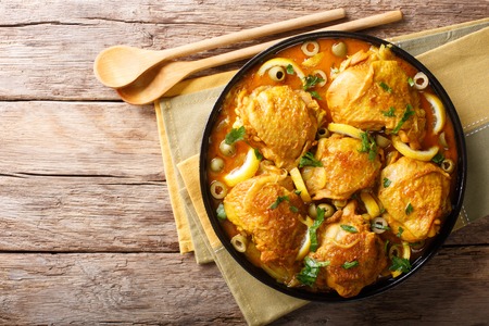 Arabian food: braised chicken with lemons, onions, spices and green olives close-up on a plate on a table. horizontal top view from aboveの写真素材
