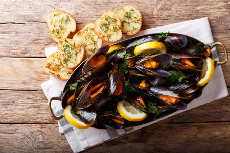 Copper pot of gourmet mussels with lemon, parsley and garlic served on a bread. Horizontal top view...