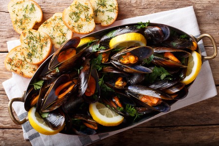 Mussels in wine with parsley and lemon. Seafood. Clams in the shells. Delicious snack for gourmands. horizontal top view from above, rustic style
の写真素材
