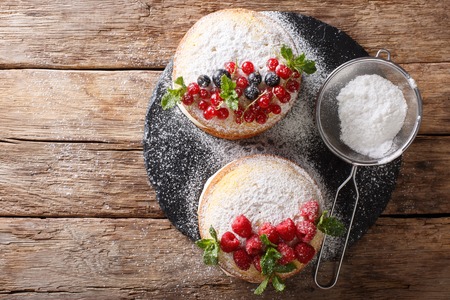 Two small Victoria cake decorated with black and red currants, raspberries and mint close-up on the table. Horizontal top view from above
の写真素材