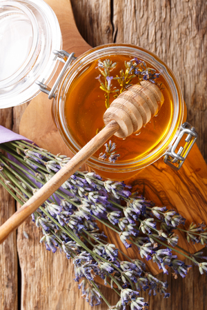 Lavender liquid honey in a glass jar close-up on a table. Vertical top view from aboveの写真素材