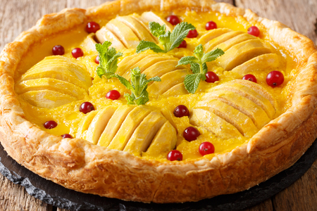 open apple pie with cranberries and custard is decorated with mint close-up on the table. horizontalの写真素材
