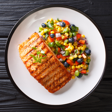 Healthy food: grilled salmon fillet with pepper, corn, blueberry and onion salad closeup on a plate on the table. top view from aboveの写真素材