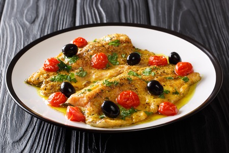 Delicious food: trout fish with garlic lemon butter sauce, tomatoes, parsley and olives closeup on a plate on a table. horizontalの写真素材