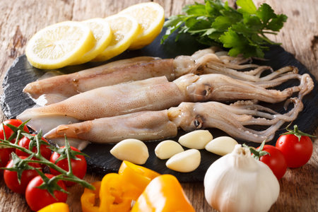 Fresh raw squid with tentacles closeup and vegetable ingredients on the table. horizontal