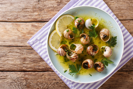French cuisine: Escargot with butter, herbs and garlic close-up on a plate on a table. horizontal top view from aboveの写真素材