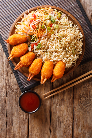 crab claws in breading, egg noodles and fresh vegetable salad close-up are served on the table. Vertical top view from aboveの写真素材