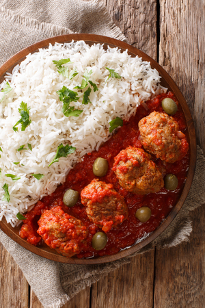 Traditional Greek meatballs in tomato sauce with rice close-up on a plate on a table. Vertical top view from aboveの写真素材
