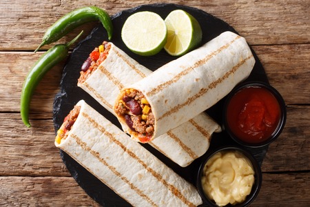 Fast food grilled burrito with beef and vegetables close-up on the table. horizontal top view from above, rustic styleの写真素材