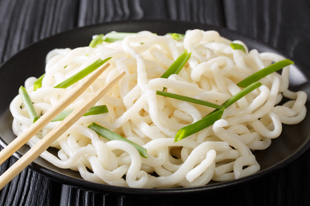 Freshly cooked udon noodles with green onions close-up on a plate on a black table. horizontalの写真素材