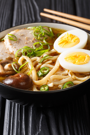 Asian soup with udon noodles, pork, eggs, shiitake and onions close-up in a bowl on the table. verticalの写真素材