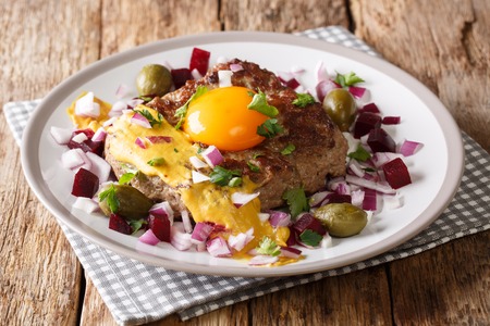 Delicious Danish Pariserbof served with raw egg yolk, mustard and vegetables close-up on a plate on the table. horizontalの写真素材