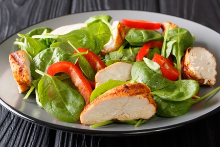 Close up of a dietary salad of fresh baby spinach, chicken breast and bell pepper on a plate on the table. horizontalの写真素材