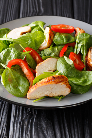 Healthy grilled chicken breast salad with fresh baby spinach and bell peppers closeup on a plate on the table. verticalの写真素材