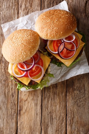 veggie burger with fresh lettuce, onions, tomatoes and cheddar cheese close-up on the table. Vertical top view from above
の写真素材
