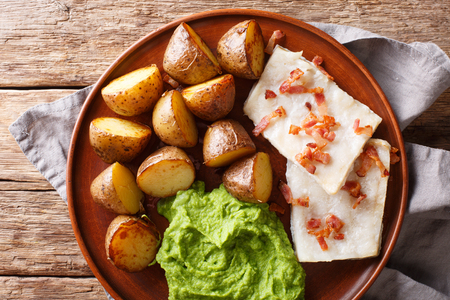 Norwegian cod lutefisk served with pea puree, potatoes and bacon close-up on a plate. Horizontal top view from above
の写真素材