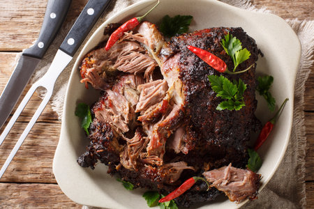Slowly cooked shredded pulled pork close-up on a plate on the table. Horizontal top view from above
