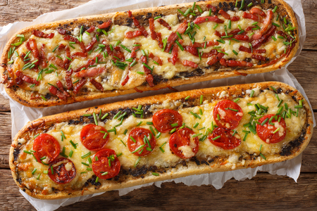 Close-up pizza sandwiches with bacon, mushrooms, tomatoes and cheese on a parchment on the table. horizontal view top from aboveの写真素材