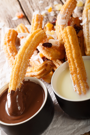 Deep-fried sweet churros served with hot chocolate and condensed milk close-up on the table. verticalの写真素材