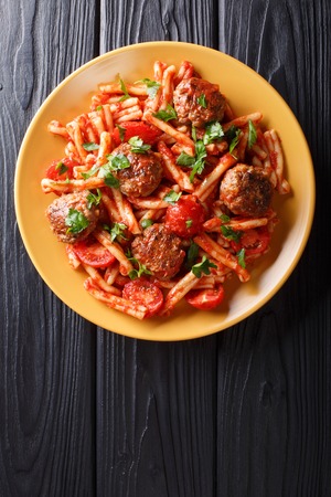 meatballs with a side dish of pasta Casarecce in tomato sauce close-up on a plate on the table. Vertical top view from above
の写真素材
