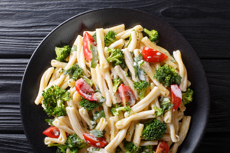 Dietary pasta Casarecce with vegetables dressed with creamy cheese sauce close-up on a plate on the table. horizontal top view from aboveの写真素材