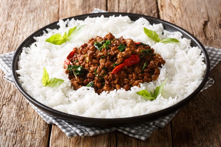Traditional basil chicken with chili pepper and soy sauce with rice garnish close-up on a plate on the table. horizontalの写真素材