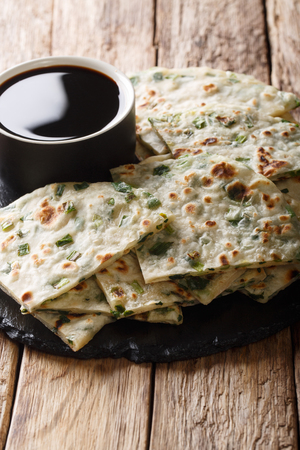 Flatbread fried onion pancakes served with sauce close-up on a board on the table. verticalの写真素材